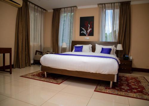 ein Schlafzimmer mit einem großen Bett mit blauen Kissen in der Unterkunft Cromer Apartments in Accra