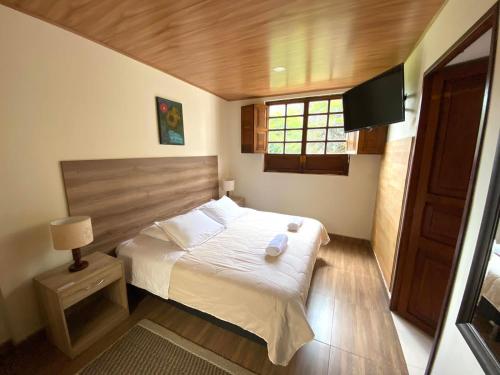 a small bedroom with a bed and a television at Hotel Villa Mercedes Colonial in Sopó