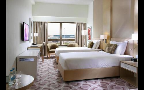 a hotel room with two beds and a large window at Metropolitain Dubai Hotel - Guest Room - UAE in Dubai