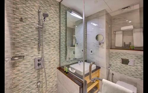 a bathroom with a sink and a shower with a mirror at Metropolitain Dubai Hotel - Guest Room - UAE in Dubai