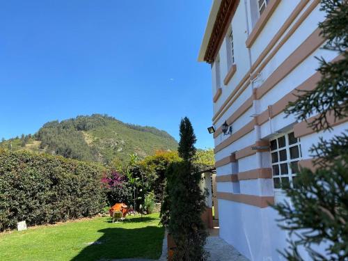 a cow standing next to a building with a mountain at Hotel Villa Mercedes Colonial in Sopó