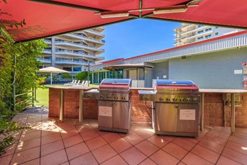 an outdoor kitchen with an umbrella on a patio at Vitina Studio Motel in Darwin