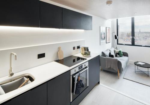 a kitchen with black cabinets and a living room at Central Manchester Duplex - Balcony - Roof Terrace - Parking in Manchester