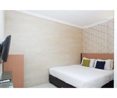 a bedroom with a bed and a flat screen tv at Capital Hotel Makassar in Pampang