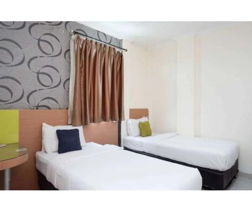a room with two beds and a window at Capital Hotel Makassar in Pampang