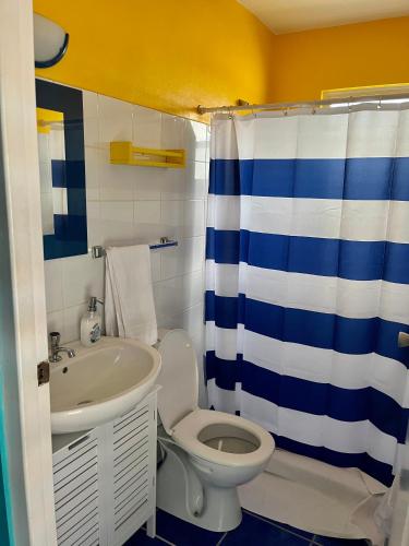 a bathroom with a blue and white shower curtain and a toilet at Marazul Dive Resort-Panoramic Ocean View Town Home in Westpunt
