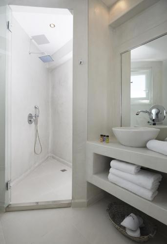a white bathroom with a sink and a mirror at Alta Vista Suites in Firostefani