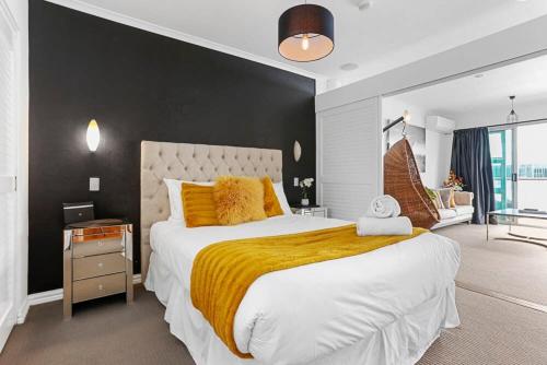 a bedroom with a large bed with a yellow blanket at Funky One Bedroom Apartment on Princes Wharf in Auckland