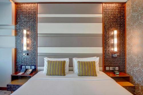 a bedroom with a large bed with two pillows at Metropolitain Dubai Hotel - Junior Suite - UAE in Dubai