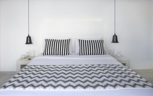 a white bed with black and white sheets and pillows at Alta Vista Suites in Firostefani