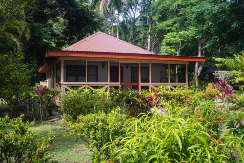 a house with a red roof in a garden at PAPAGENO RESORT & DIVE in Kadavu