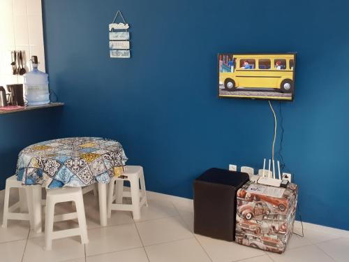 a blue room with a table and a yellow bus on the wall at Apartamento 101 com vista da piscina e mar in Piúma