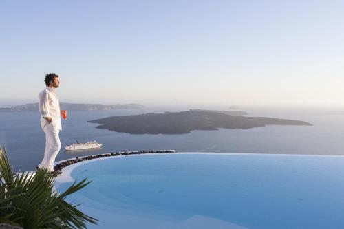 a man standing on the edge of a swimming pool at Alta Vista Suites in Firostefani