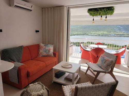 a living room with a red couch and a balcony at Appartement neuf design - Résidence avec piscine in Cul de Sac