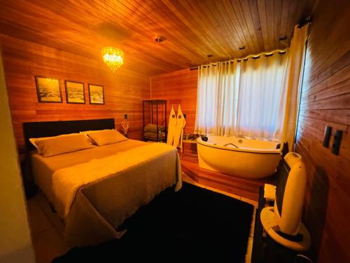 um quarto com uma cama e uma banheira em Recanto Ar da Serra em São Joaquim