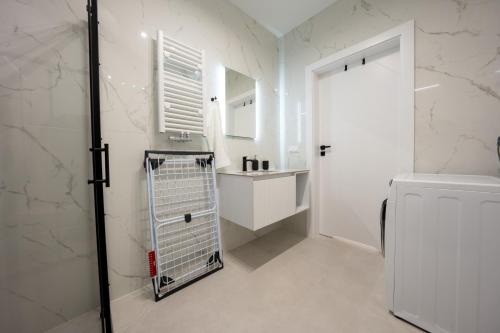 a white bathroom with a sink and a toilet at Miodowy apartament z dużym tarasem w Rewalu, blisko morza in Rewal