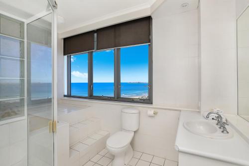 a bathroom with a toilet and a sink and a window at Majorca Isle Beachside Resort in Maroochydore