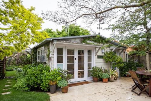 Ce petit cottage blanc dispose d'une terrasse. dans l'établissement Silk Tree Studio - Steps to Cook Park, à Orange