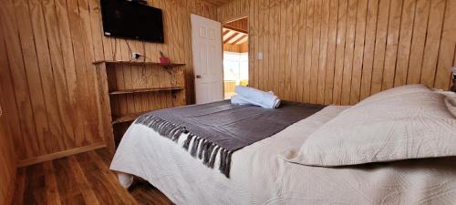 Schlafzimmer mit einem Bett und einem Flachbild-TV in der Unterkunft Cabañas Antü Küyen Melipeuco in Melipeuco