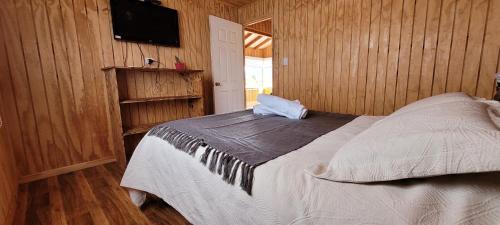 a bedroom with a bed and a flat screen tv at Cabañas Antü Küyen Melipeuco in Melipeuco