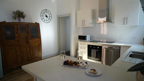 a kitchen with a plate of food and two glasses of wine at Stay on Summer - CBD Apartment in Orange