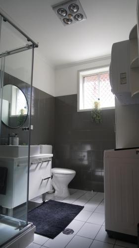 a bathroom with a toilet and a sink and a mirror at Stay on Summer - CBD Apartment in Orange