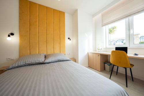 a bedroom with a large bed and a yellow chair at Miodowy apartament z dużym tarasem w Rewalu, blisko morza in Rewal