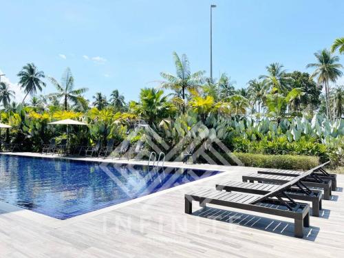 a pool at a resort with benches and palm trees at Roxy Sematan Beach Townhouse Deluxe 3 ,5 & 6 in Sematan