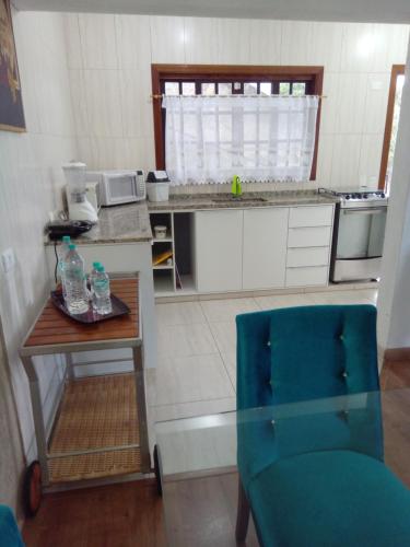 a small kitchen with a table and a blue chair at Casa dos Neves in Campos do Jordão