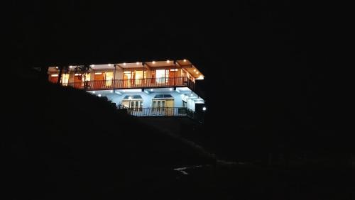 a large house with a balcony at night at Kavyansh Forest Valley in Dalhousie