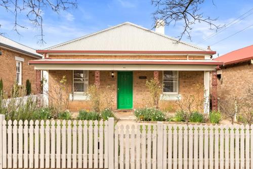 a brick house with a green door behind a fence at Ambrose On Byng - Central Location in Orange