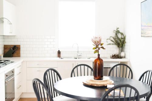eine Küche mit einem Tisch mit Stühlen und einer Vase mit einer Blume in der Unterkunft Birchfrost Cottage - Elevated Heritage Aesthetic in Orange