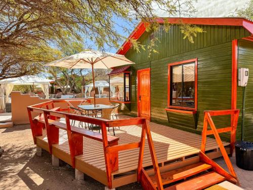 a green house with a table and an umbrella at Lodge Ancar Atacama in San Pedro de Atacama