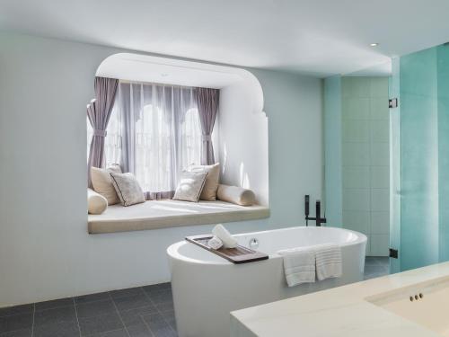 a bathroom with a bath tub and a mirror at Sarai Resort & Spa and The Wander in Siem Reap