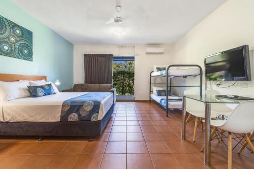 a bedroom with a bed and a desk and a table at Vitina Studio Motel in Darwin