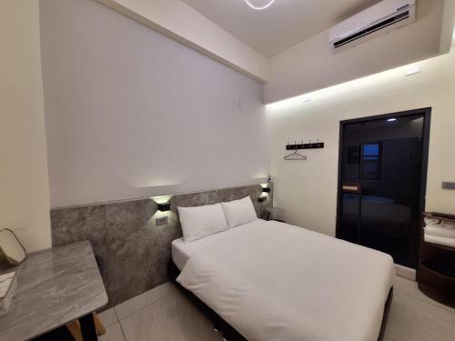 a hotel room with a white bed and a desk at 安平包棟民宿 - 尋雨 - 部分日期可預定散房-台南民宿園景採光豪宅 in Tainan