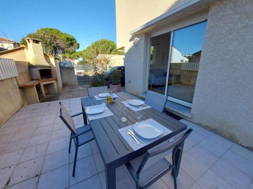 une table et des chaises en bois sur une terrasse dans l'établissement Maison T3 Climatisée à 150m de la Plage avec Terrasse et Parking, Tout à Pied! - FR-1-423-307, au Grau-dʼAgde