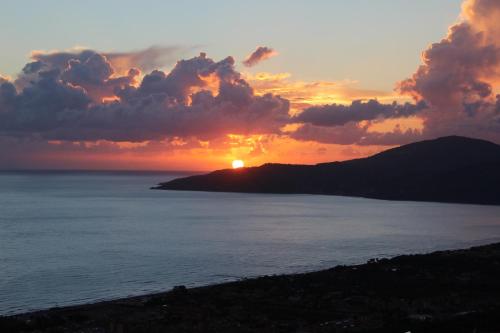 a sunset over the ocean with a hill in the background at La Terrazza sul Mare in Ascea