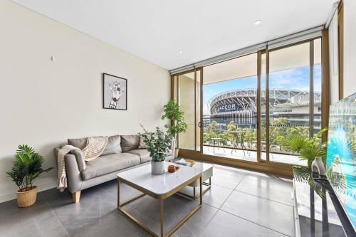 a living room with a couch and a large window at Olympic Park Stadium Cozy 1 bedroom Apt in Sydney