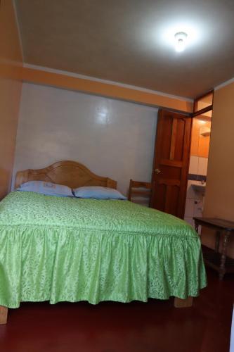 a bedroom with a bed with a green bedspread at Hospedaje MALVIN Motoposada in Pitumarca