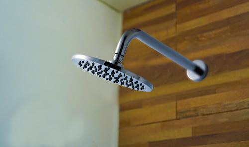 a shower head in a bathroom with a wooden wall at Dirga's House Sanur View by EPS in Sanur