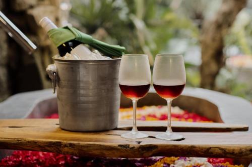 two glasses of wine on a table with a bucket of champagne at Agastya Ubud Villa in Ubud