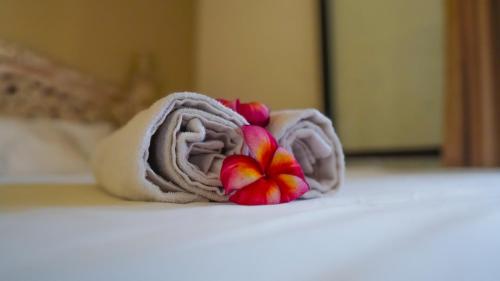 a towel with a flower sitting on a table at Dirga's House Sanur View by EPS in Sanur