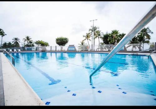 a large swimming pool with blue water and palm trees at Downtown Beachfront Isla Verde Luxury Apartment in San Juan