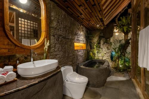 a bathroom with a sink and a toilet and a tub at Agastya Ubud Villa in Ubud