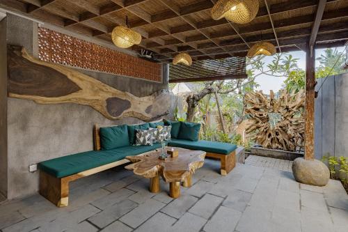 a patio with a green couch and a wooden table at Agastya Ubud Villa in Ubud
