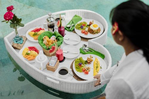 a woman sitting on a table with plates of food at Agastya Ubud Villa in Ubud