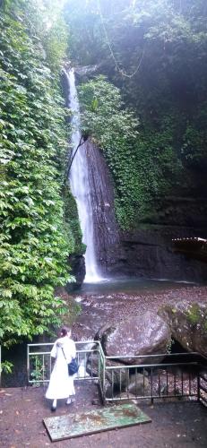 a woman in a white dress standing in front of a waterfall at Tetebatu Fullmoon in Tetebatu