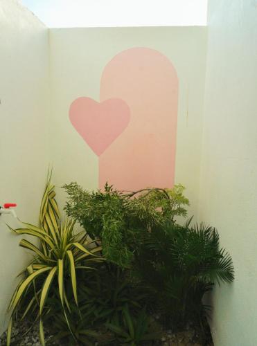 a painting of a heart on a wall next to plants at Pink Sea Villa in Cu Lao Thu