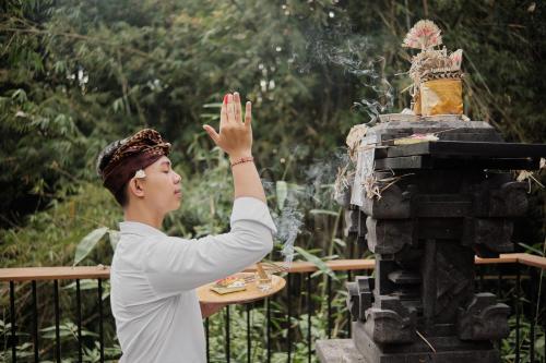 a woman standing next to a fountain with her hand in the air at Agastya Ubud Villa in Ubud